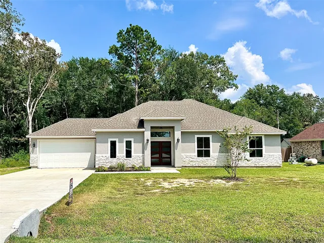 a front view of a house with a yard and potted plants