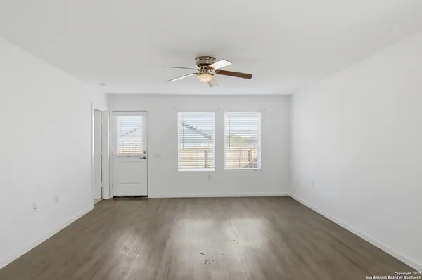 an empty room with wooden floor and chandelier fan