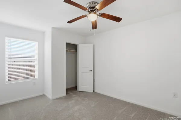 an empty room with a ceiling fan and a window