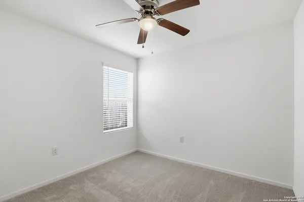 an empty room with a window and a ceiling fan