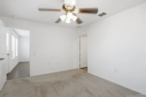 an empty room with a chandelier fan and closet