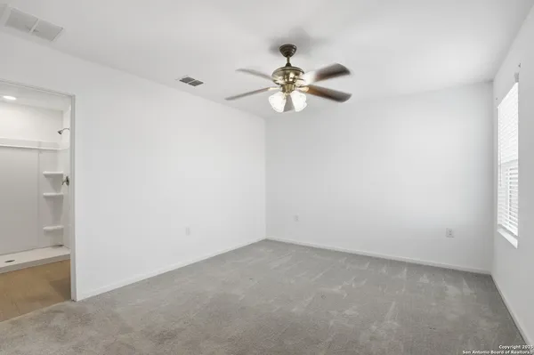 an empty room with a window and a fan