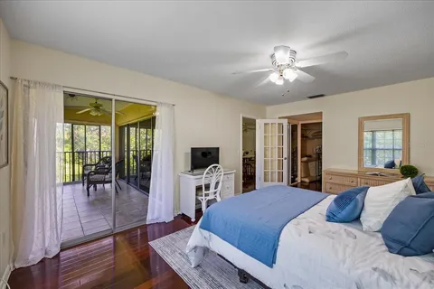 a bedroom with a large bed a flat tv screen and balcony