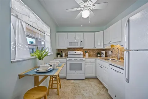 a kitchen with stainless steel appliances a white table chairs and a window