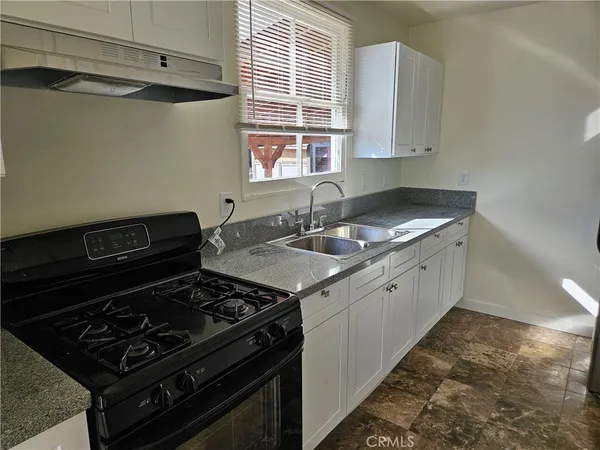 a kitchen with granite countertop a stove and a sink