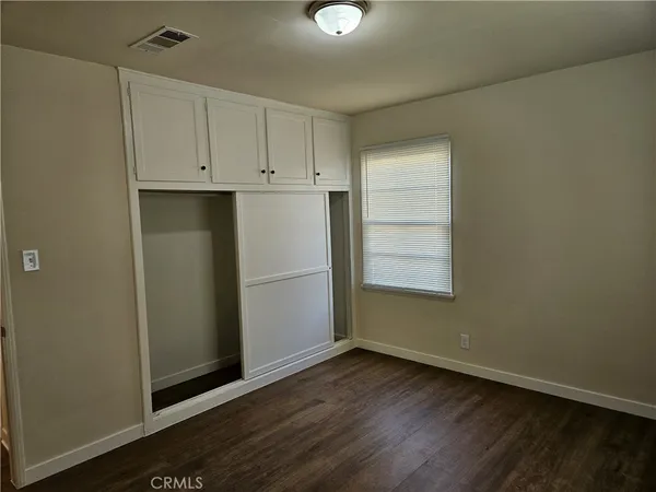 an empty room with wooden floor cabinet and windows