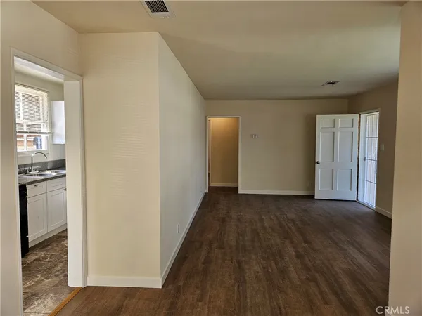 a view of a hallway with wooden floor and a kitchen