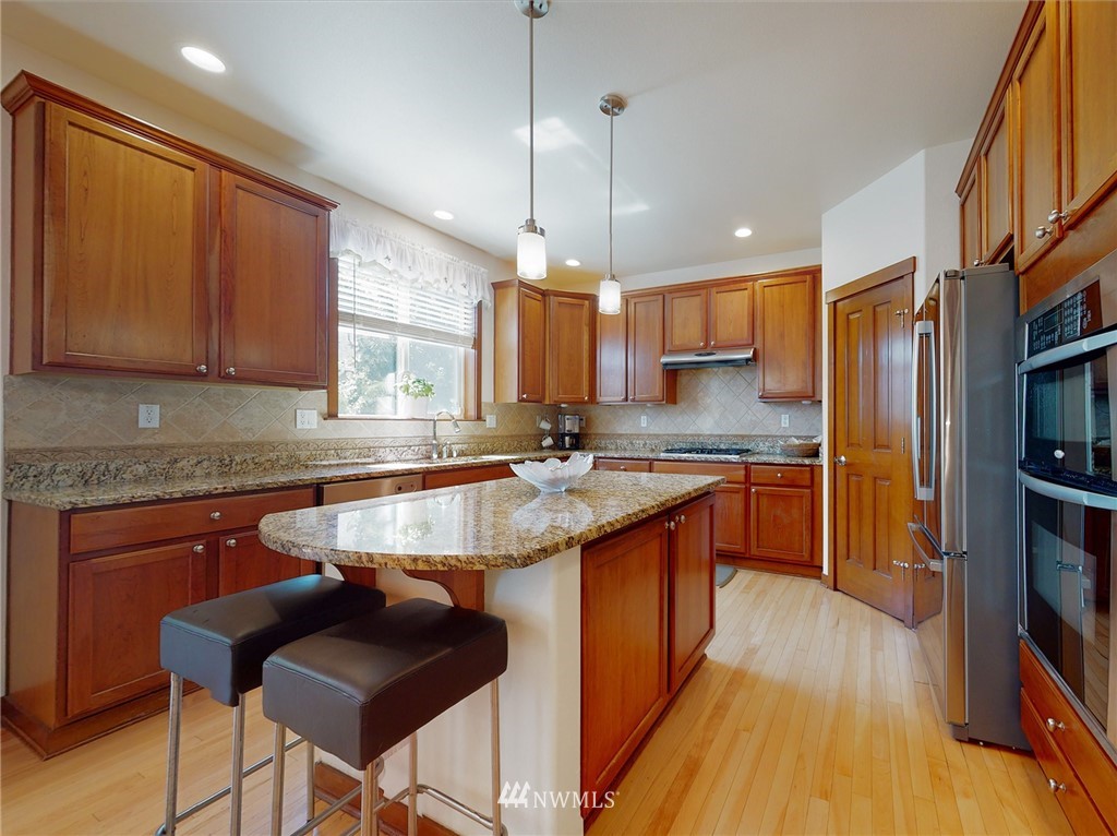 4002 216th Place Southeast Bothell, WA 98021 - Photo 12 of 28 a kitchen with stainless steel appliances granite countertop a sink a stove a refrigerator cabinets and wooden floor