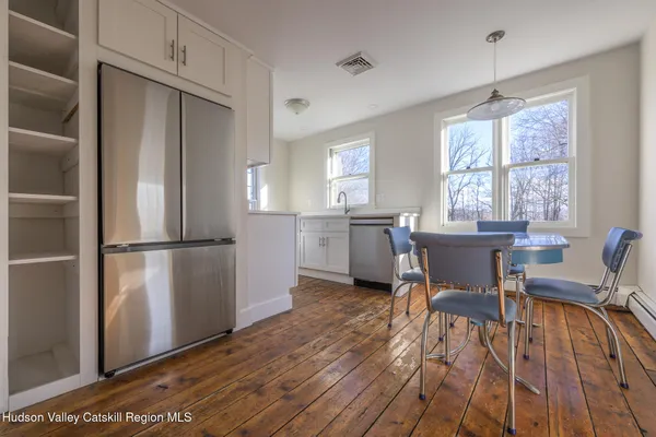 a kitchen with stainless steel appliances a dining table chairs refrigerator and sink