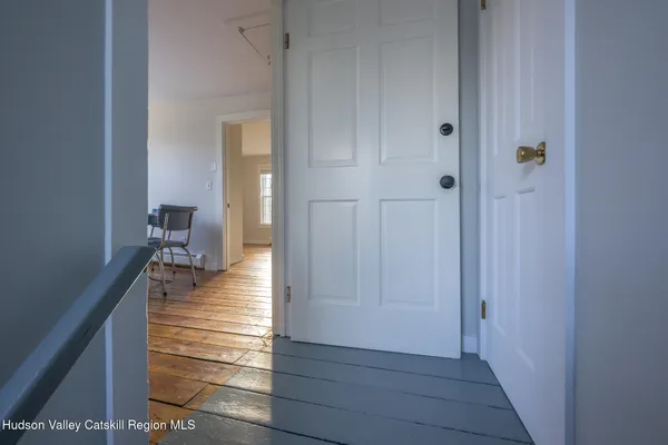 a hallway with white doors wooden floor and stairs