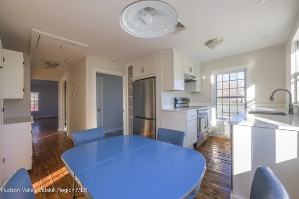 a living room with stainless steel appliances furniture a large window and a kitchen view