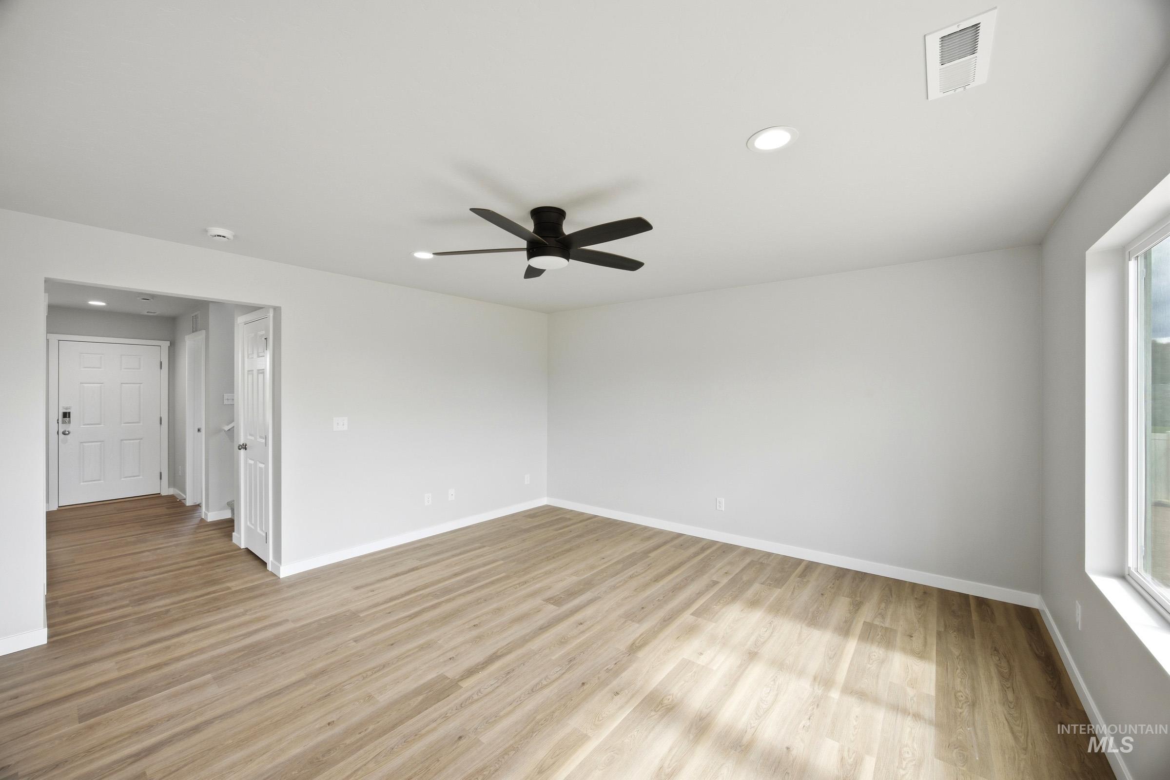 14044 Shiny Spruce Street Caldwell, ID 83607 - Photo 8 of 24 Spacious room featuring wood-finish flooring, a contemporary ceiling fan, recessed lighting, and a large window