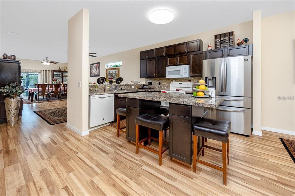 7820 Harbor Bridge Boulevard New Port Richey, FL 34654 - Photo 6 of 24 a kitchen with stainless steel appliances a dining table chairs stove refrigerator and cabinets