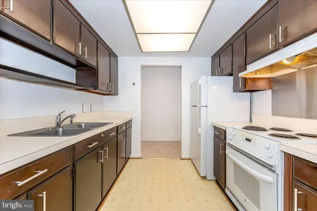 a kitchen with stainless steel appliances a refrigerator a sink and white cabinets