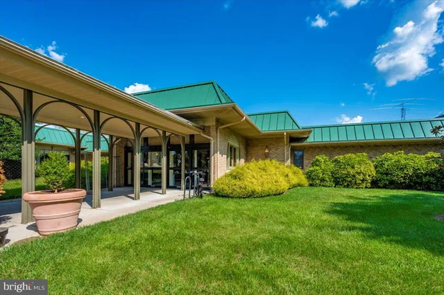 a view of a house with a yard and table and chairs under an umbrella