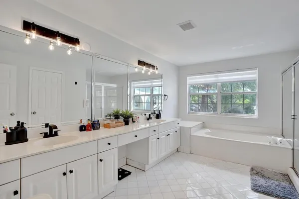 a spacious bathroom with double vanity sink a mirror a window and vanity