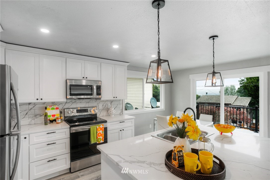 405 Maple Avenue Northwest Renton, WA 98057 - Photo 8 of 23 a kitchen with stainless steel appliances kitchen island granite countertop a sink a stove and a wooden floor