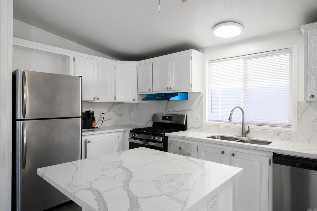 400 Greenfield Drive El Cajon, CA 92021 - Photo 17 of 41 a kitchen with a refrigerator a stove a sink and white cabinets
