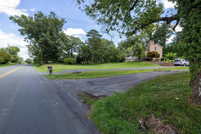 a view of a street with a yard and trees
