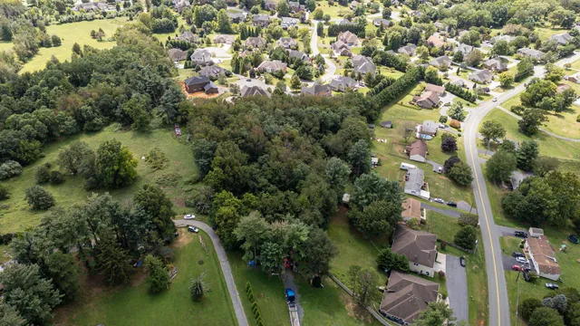 an aerial view of residential houses with outdoor space and trees all around