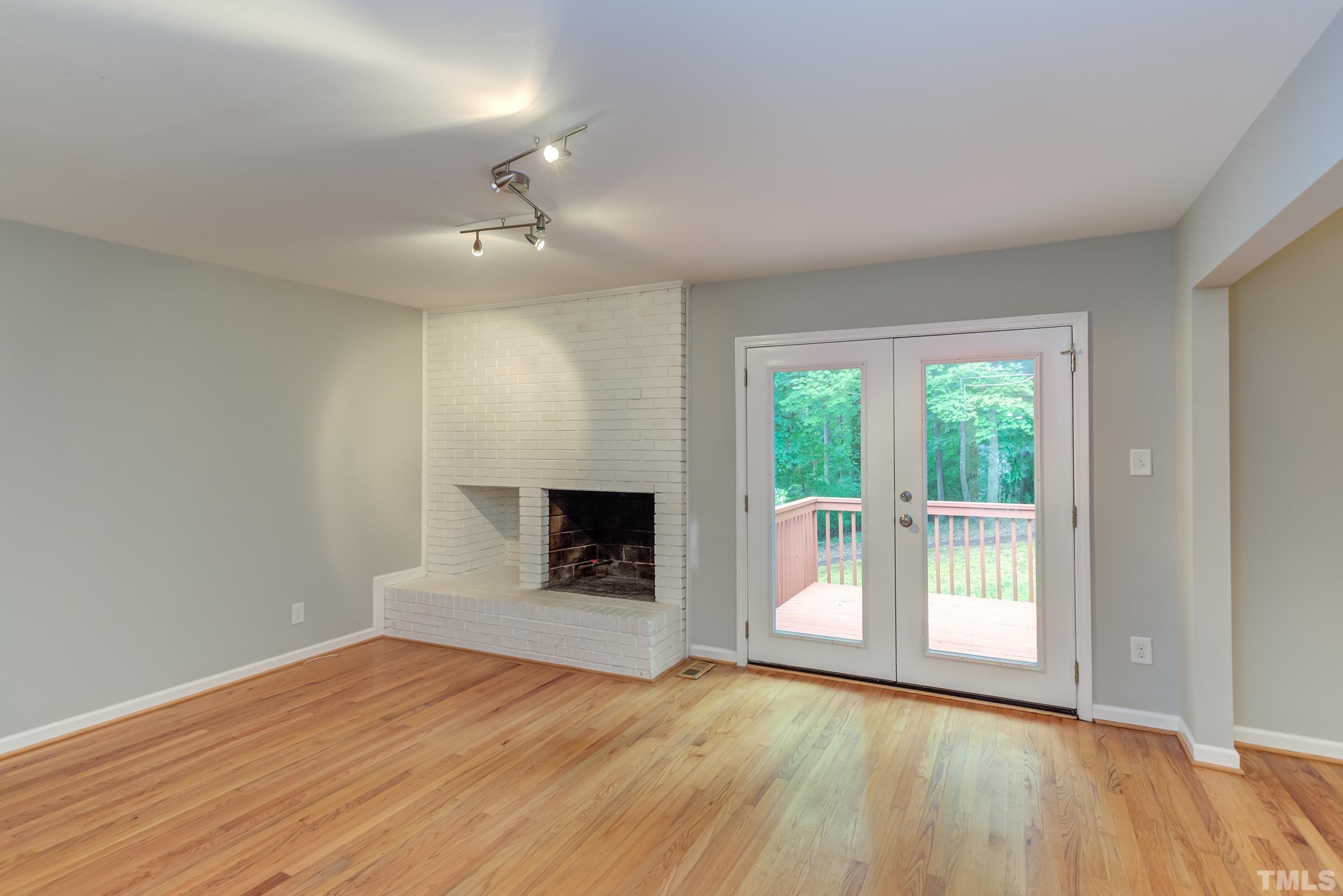 912 Winona Road Raleigh, NC 27609 - Photo 10 of 30 an empty room with wooden floor fireplace and windows