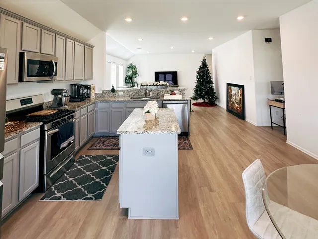 a kitchen with granite countertop a stove top oven a sink dishwasher a refrigerator and cabinets with wooden floor