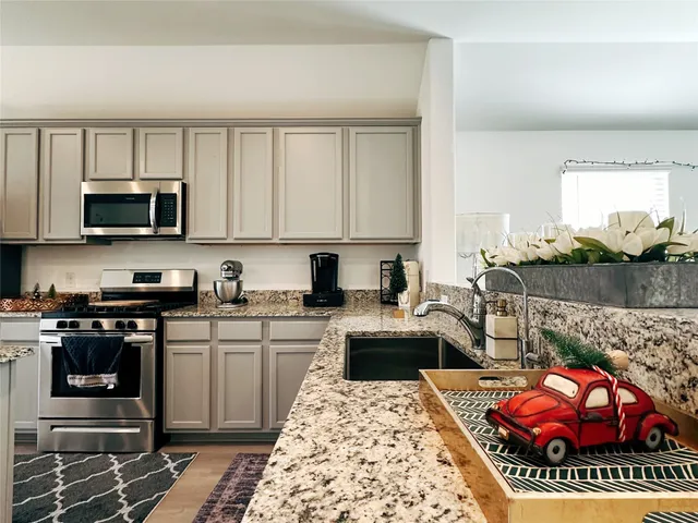 a kitchen with stainless steel appliances granite countertop a stove top oven a sink dishwasher and cabinets with wooden floor