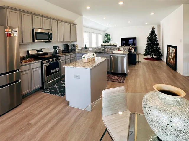 a kitchen with stainless steel appliances granite countertop a stove a sink a refrigerator and a microwave