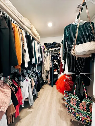 a view of walk in closet with clothes and shoes