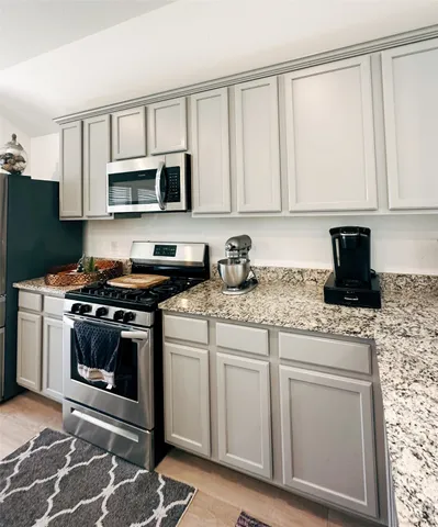 a kitchen with stainless steel appliances granite countertop a stove a sink and a microwave
