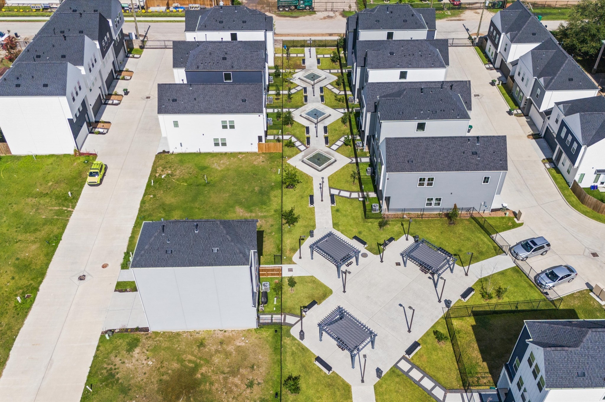 8319 Springwood Drive Houston, TX 77055 - Photo 37 of 47 From above, Springwood Villas reveals its harmonious blend of architecture, greenery, and shared spaces. Homes are arranged in elegant rows, connected by winding pathways that lead to a central community courtyard—a lush oasis featuring pergolas, shaded seating, and water fountains.