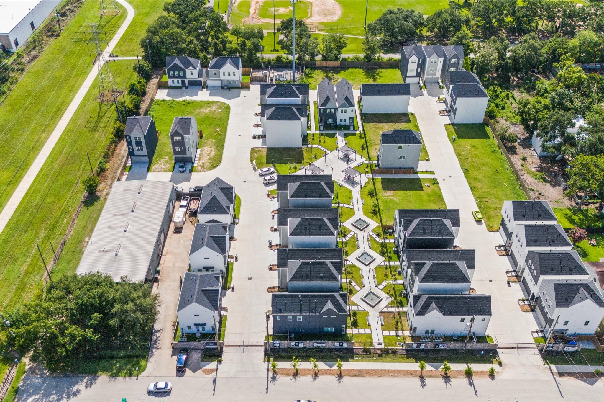 8319 Springwood Drive Houston, TX 77055 - Photo 38 of 47 From above, Springwood Villas reveals its harmonious blend of architecture, greenery, and shared spaces. Homes are arranged in elegant rows, connected by winding pathways that lead to a central community courtyard—a lush oasis featuring pergolas, shaded seating, and water fountains.