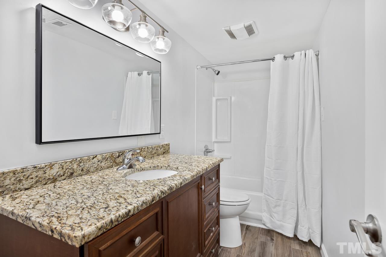 7002 Longstreet Drive, Unit C Raleigh, NC 27615 - Photo 15 of 18 a bathroom with a granite countertop sink and a mirror