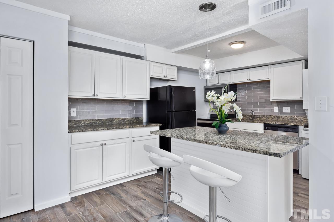 7002 Longstreet Drive, Unit C Raleigh, NC 27615 - Photo 6 of 18 a kitchen with stainless steel appliances granite countertop a stove a sink and a refrigerator