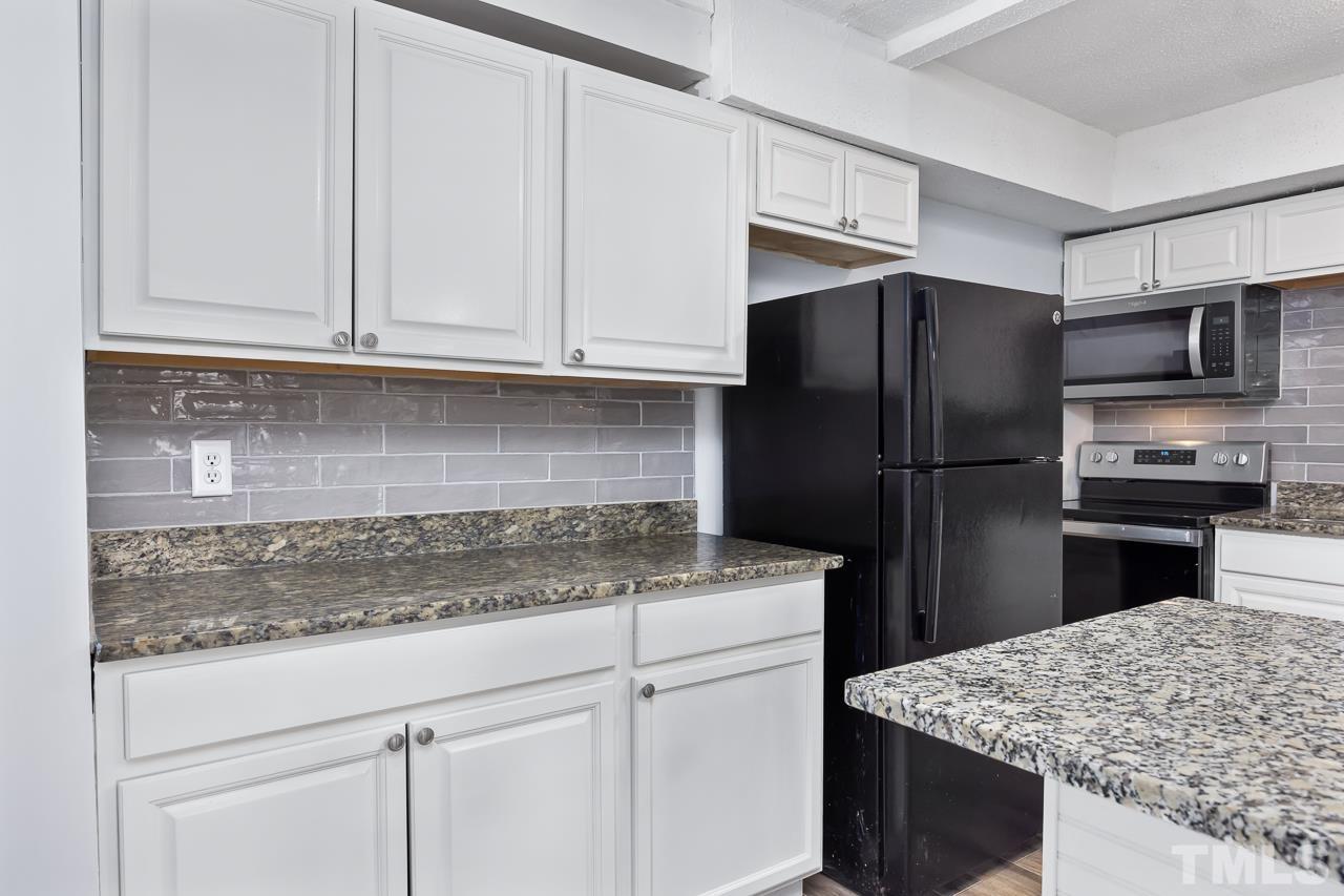 7002 Longstreet Drive, Unit C Raleigh, NC 27615 - Photo 7 of 18 a kitchen with granite countertop wooden cabinets and refrigerator