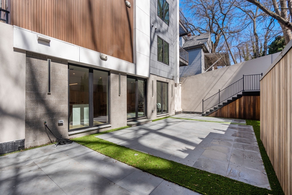 57 University Road, Unit 1 Brookline, MA 02445 - Photo 1 of 25 a view of a white house with a small yard and wooden fence
