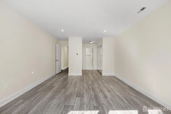 a view of an empty room with wooden floor and a bathroom