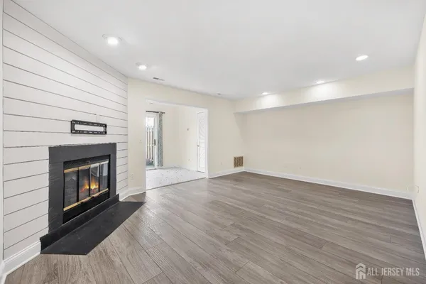 a view of an empty room with wooden floor fireplace and a window