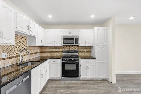 a kitchen with granite countertop white cabinets and stainless steel appliances