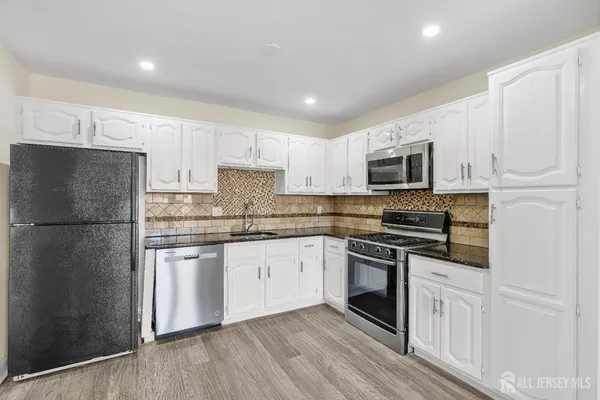 a kitchen with granite countertop white cabinets and stainless steel appliances