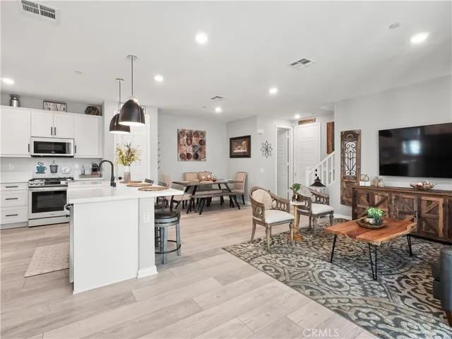 a living room with stainless steel appliances kitchen island granite countertop a couch and a flat screen tv