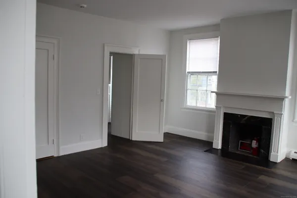 an empty room with wooden floor fireplace and windows
