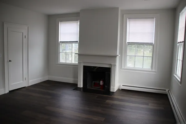 an empty room with wooden floor windows and a fireplace