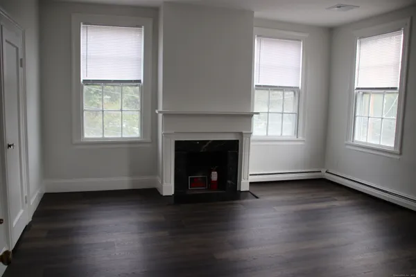 an empty room with wooden floor windows and a fireplace