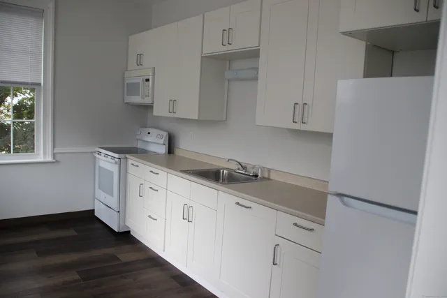 a kitchen with granite countertop white cabinets and sink
