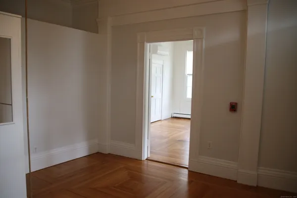 a view of an empty room with wooden floor and closet