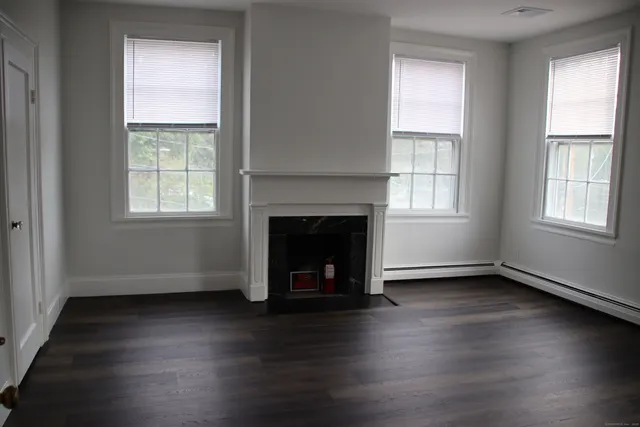 an empty room with wooden floor windows and a fireplace