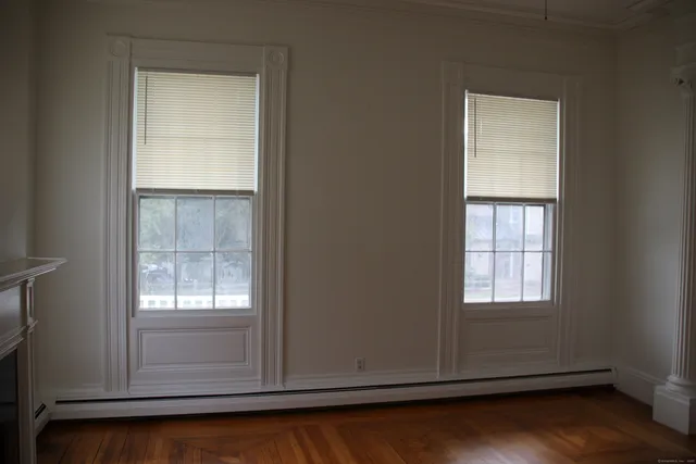 an empty room with wooden floor closet and windows