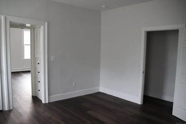 a view of an empty room with wooden floor and closet