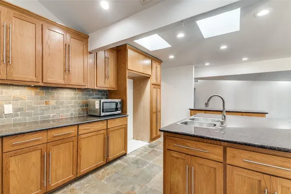 a kitchen with stainless steel appliances granite countertop a sink a stove and a refrigerator